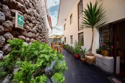a courtyard with potted plants and tables and a building at Hotel Boutique Gold Garden in Cusco