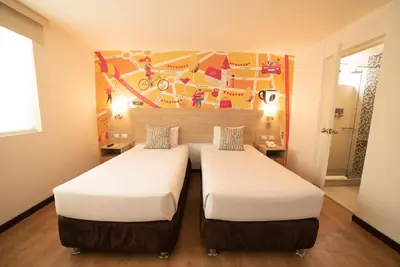 two beds in a room with a mural on the wall at Centro by Casa Andina Miraflores in Lima