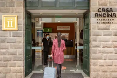 a woman walking into a building with a suitcase at Casa Andina Standard Cusco Catedral in Cusco