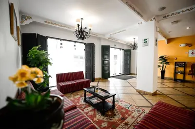 a living room with a red couch and a table at Hotel Raymi in Cusco