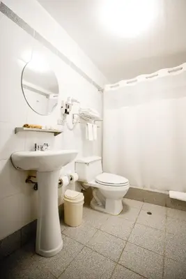 a white bathroom with a sink and a toilet at Hotel Raymi in Cusco