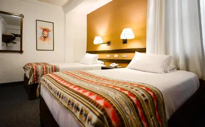 a hotel room with two beds and a mirror at Hotel Raymi in Cusco