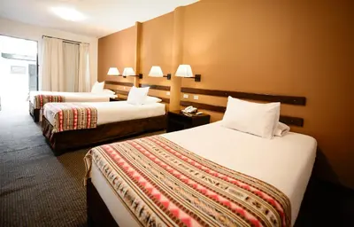 a hotel room with two beds and a window at Hotel Raymi in Cusco