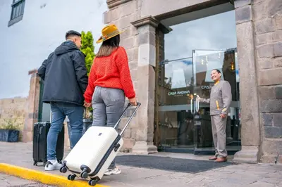 a man and a woman with a suitcase outside a store at Casa Andina Premium Cusco in Cusco