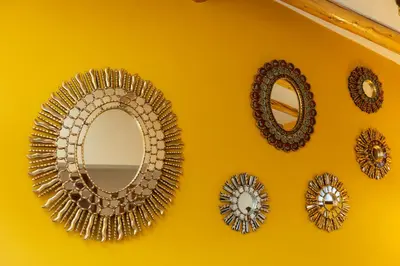 a group of mirrors on a yellow wall at Amerindia in Cusco