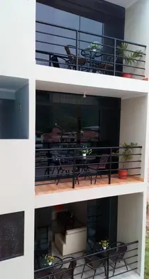 two views of a balcony with a table and chairs at Maudi Lodging in La Merced