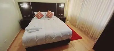 a bedroom with a large white bed with a red rug at Hotel Mantas Cusco in Cusco