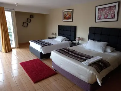 a bedroom with two beds and a red rug at Hotel Mantas Cusco in Cusco