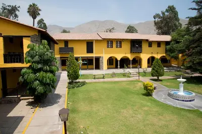 a yellow building with a large yard with a park at Decameron El Pueblo in Lima