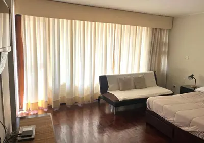 a bedroom with a bed and a chair in front of a window at Lima Mini Aparts Monterrico - Cerca Embajada EEUU in Lima