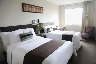 a hotel room with two beds and a chair at Hotel Rivera Inn in Lima