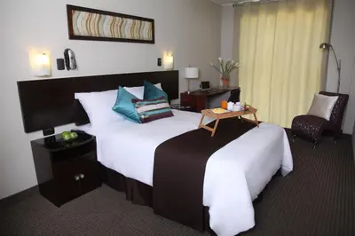 a hotel room with a large bed and a chair at Hotel Rivera Inn in Lima