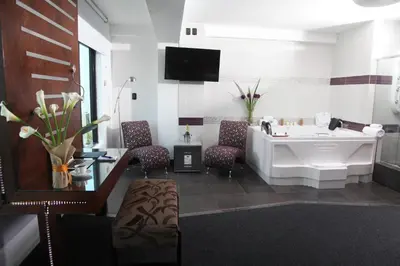 a bathroom with a tub and a sink and chairs at Hotel Rivera Inn in Lima