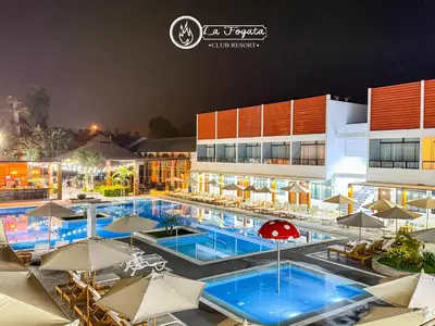 a resort pool with umbrellas and tables and chairs at Resort la Fogata Cieneguilla in Cieneguilla