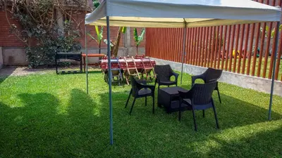 a table and chairs under an umbrella in the grass at Resort la Fogata Cieneguilla in Cieneguilla