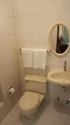 a white bathroom with a toilet and a sink at Hotel Internacional in Lima