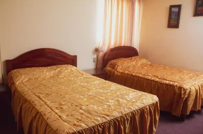 two beds in a hotel room with orange sheets at Hotel Internacional in Lima