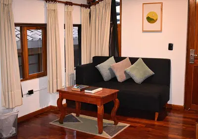 a living room with a black couch and a table at Nodo Cusco Garcilaso in Cusco