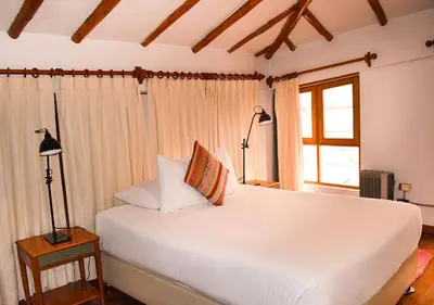 a bedroom with a large white bed and a window at Nodo Cusco Garcilaso in Cusco