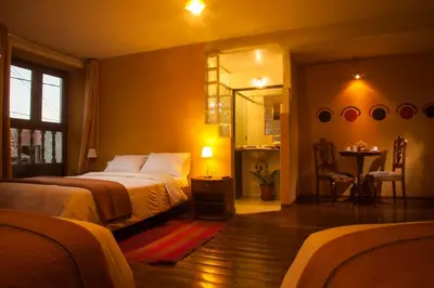 a bedroom with a bed and a table and a mirror at Eureka San Blas in Cusco