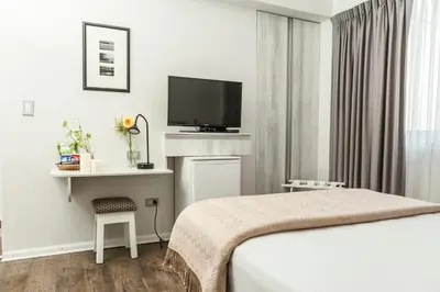a hotel room with a bed and a flat screen tv at La Paz Apart Hotel in Lima