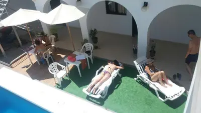 two people sitting in lawn chairs next to a swimming pool at La Maison de Lydia in Nazca