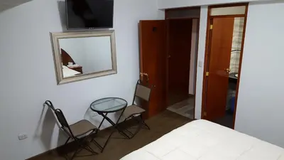 a bedroom with a bed and two chairs and a mirror at Hotel Shelter in Huancayo