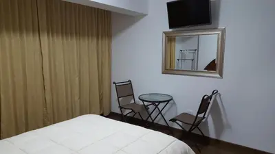 a bedroom with a bed and two chairs and a table at Hotel Shelter in Huancayo