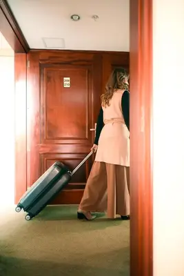 a woman pulling a suitcase in a hallway at Los Tallanes Hotel & Suites in Lima