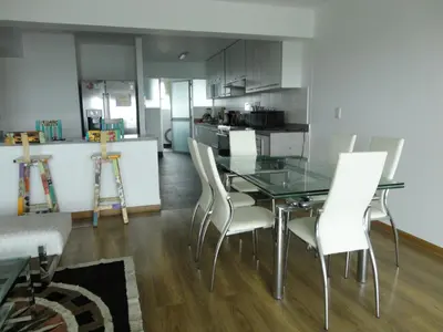 a dining room with a glass table and white chairs at San Borja, bello apartamento in Lima