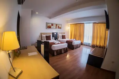 a hotel room with two beds and a couch at Allpa Hotel & Suites in Lima