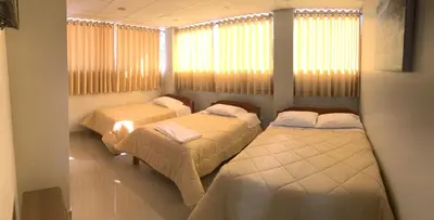 two beds in a room with windows and curtains at Edmoli Casa Hospedaje in Cusco