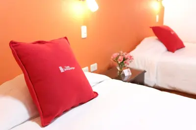 a hotel room with two beds with red pillows at Hotel Limacpampa in Cusco
