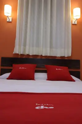 a bed with two red pillows on top of it at Hotel Limacpampa in Cusco