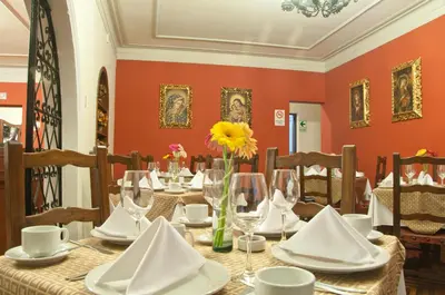 a dining room with a table with glasses and flowers at Hotel San Isidro Inn in Lima