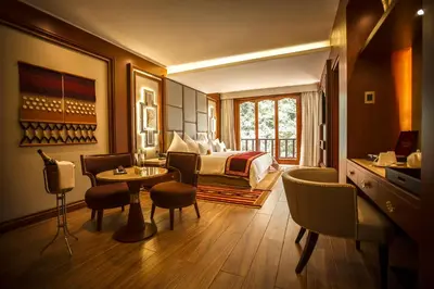 a hotel room with a bed and a table and chairs at Sumaq Machu Picchu Hotel in Machu Picchu