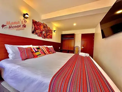 a bedroom with a large white bed with colorful pillows at Mama's House in Cusco