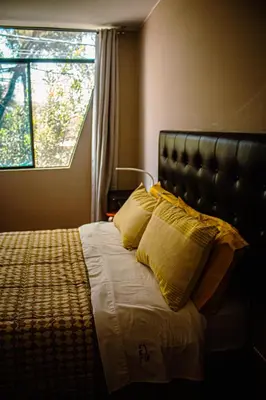 a bedroom with a bed with yellow pillows and a window at Del Valle House in Ica
