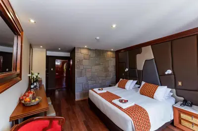 a hotel room with a large bed and a red chair at Yawar Inka Hotel in Cusco