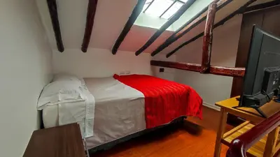 a bedroom with a bed with a red blanket at La Casa de Laura - Plaza in Cusco
