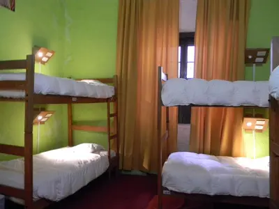 three bunk beds in a room with a window at Pirwa Backpackers Colonial in Cusco