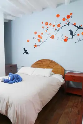 a bedroom with a bed with a tree mural on the wall at Pirwa Backpackers Colonial in Cusco