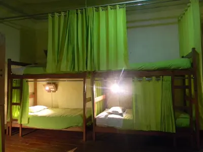 two bunk beds in a room with green curtains at Pirwa Backpackers Colonial in Cusco