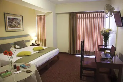 a hotel room with a bed and a table and a desk at Kamana Hotel in Lima