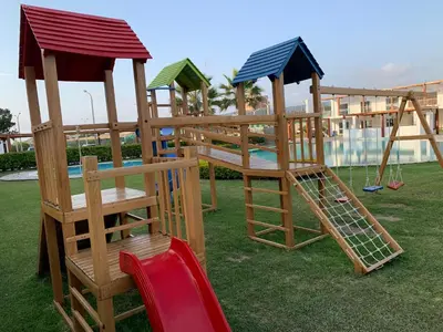 a group of wooden play structures sitting on the grass at La Casa del Jota in Asia