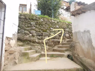 a set of stairs with a yellow rail next to a stone wall at Wichana Wasi in Cusco