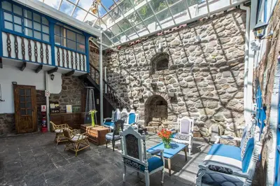 a patio with chairs and a stone wall at X.O Art House in Cusco
