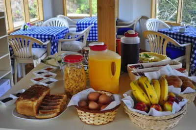 a table topped with baskets of breakfast foods and orange juice at San Alberto Ecolodge in Oxapampa