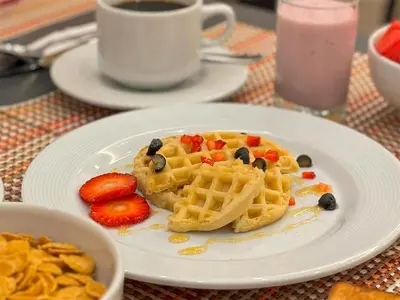 a plate with waffles and strawberries and a cup of coffee at Best Western Plus Urban Larco Hotel in Lima