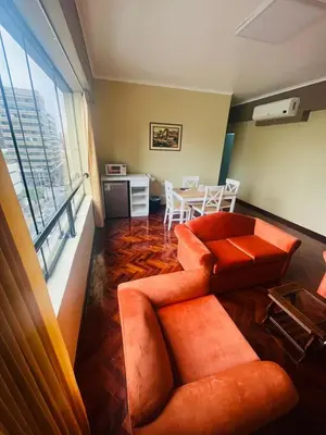 a living room with two orange chairs and a table at Suites Larco 656 Miraflores Lima in Lima